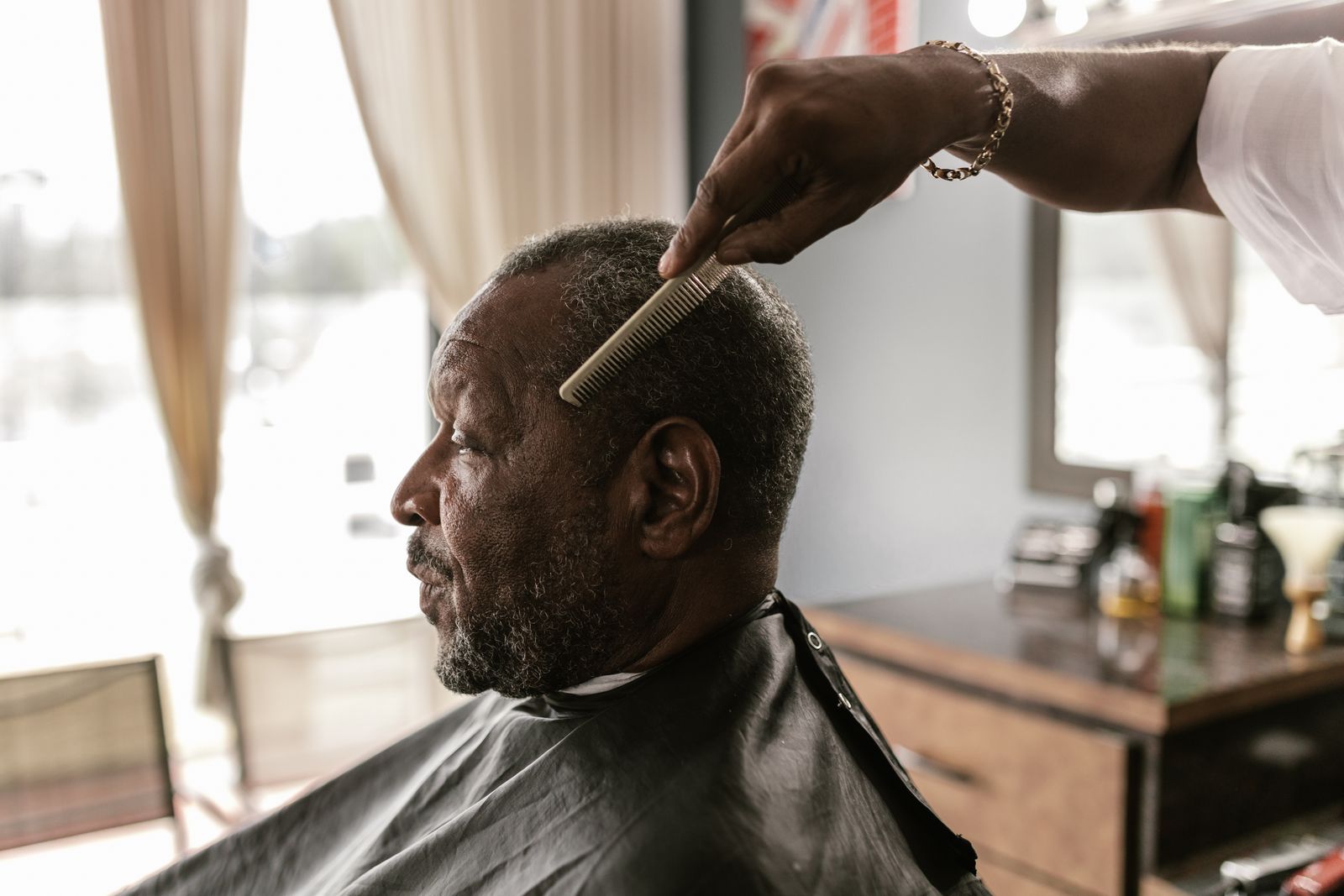 Barbeiro finalizando o corte de um cliente maduro