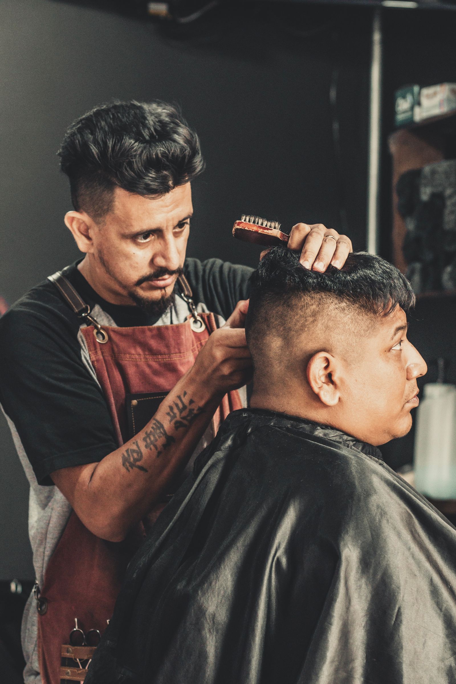 Barbeiro finalizando o penteado de um cliente